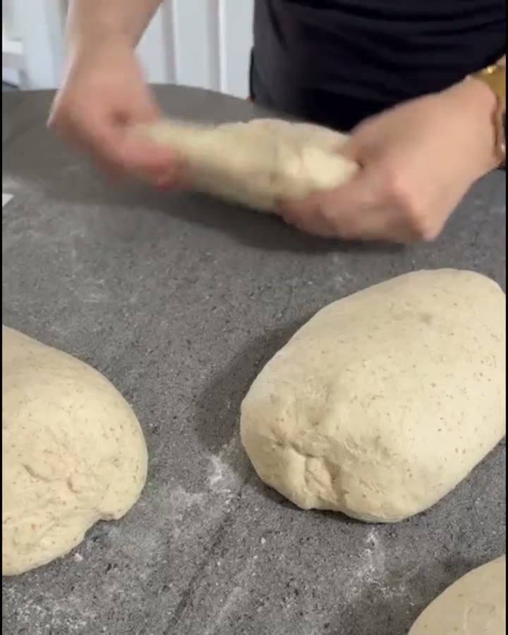 Hands shaping sourdough on a floured counter.
